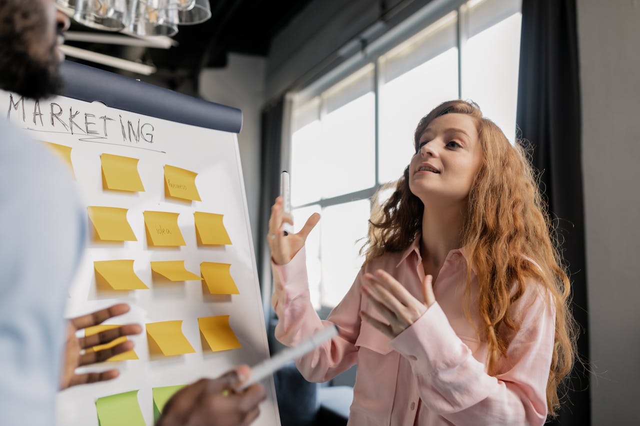 Woman in a business meeting discussing marketing strategies using sticky notes on a board.